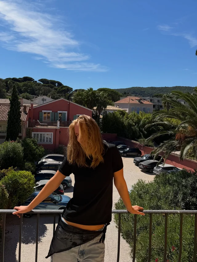 sofia on a balcony in Saint-Tropez, black tee, hair over her face