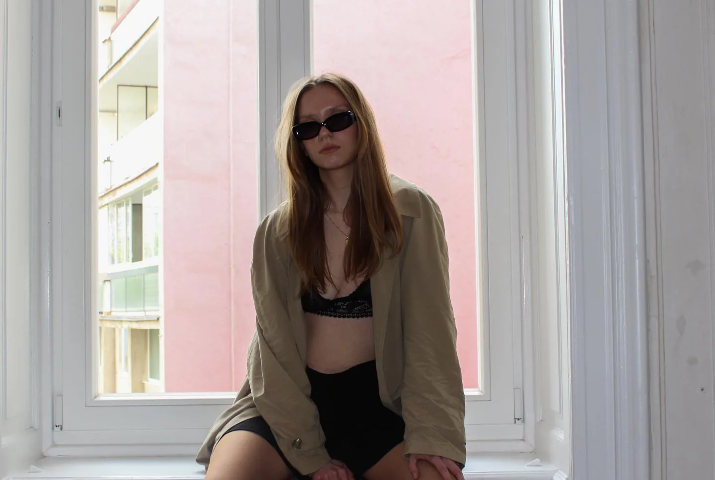 At a window with a pink wall